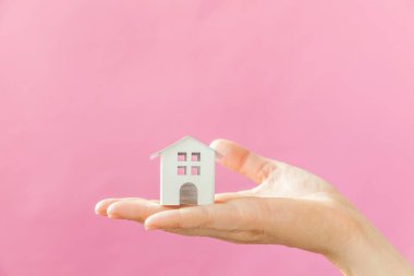 Sadece pembe pastel renkli trendy arka plan izole minyatür beyaz oyuncak ev tutan kadın kadın el tasarımı