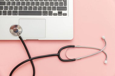 Pembe arka plan üzerinde izole Stetoskop klavye dizüstü bilgisayar. Modern tıbbi Bilgi teknolojisi ve sofware gelişmeler kavramı. Bilgisayar ve gadget tanılama ve onarım