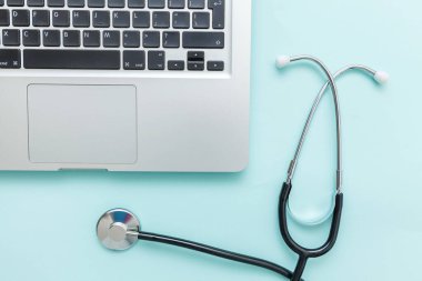 Stetoskop klavye dizüstü bilgisayarı mavi arkaplanda izole edilmiş. Modern tıbbi bilgi teknolojisi ve yazılımlar konsepti geliştirir. Bilgisayar ve aygıt tanılama ve onarım