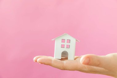 Sadece pembe pastel renkli trendy arka plan izole minyatür beyaz oyuncak ev tutan kadın kadın el tasarımı