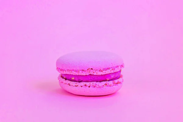 Sweet almond colorful unicorn pink macaron or macaroon dessert cake isolated on trendy pink pastel background. French sweet cookie. Minimal food bakery concept. Copy space