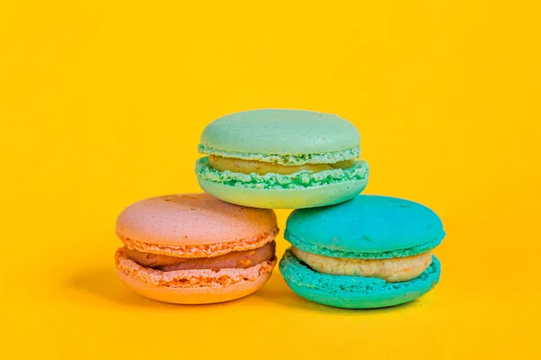 Sweet almond colorful unicorn pink blue yellow green macaron or macaroon dessert cake isolated on trendy yellow modern fashion background. French sweet cookie. Minimal food bakery concept. Copy space