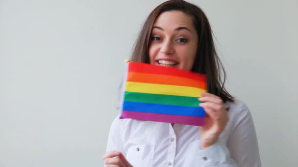 Hermosa chica lesbiana caucásica con bandera de arco iris LGBT aislada sobre fondo blanco mirando feliz y emocionado. Mujer joven retrato del Orgullo Gay. Igualdad de derechos para el concepto de comunidad lgbtq. — Vídeo de stock