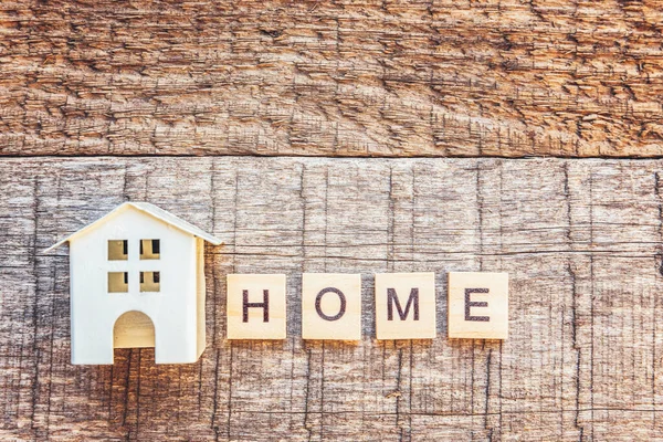 Miniaturowy domek z napisem HOME litery słowo na drewnianym tle. Ubezpieczenie nieruchomości hipotecznych wymarzone pojęcie domu. Płaski widok z góry, przestrzeń kopiowania — Zdjęcie stockowe