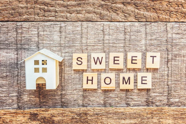 Casa de brinquedo em miniatura com inscrição SWEET HOME letras palavra sobre fundo de madeira. hipoteca propriedade seguro sonho casa conceito. Flat lay vista superior, espaço de cópia — Fotografia de Stock