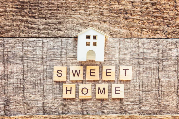 Miniatur-Spielzeughaus mit der Aufschrift SWEET HOME Buchstaben Wort auf Holzgrund. Hypothekenversicherungen träumen von einem Eigenheim. Flache Lageansicht, Kopierraum — Stockfoto