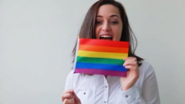 Beyaz arka planda izole edilmiş LGBT gökkuşağı bayraklı güzel beyaz lezbiyen kız mutlu ve heyecanlı görünüyor. Genç kadın Gay Gurur portresi. lgbtq topluluk kavramı için eşit haklar