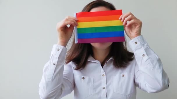 白地にLgbtの虹の旗が描かれた美しい白人レズビアンの女の子は幸せそして興奮しています 若い女性ゲイの誇りの肖像画 Lgbtqコミュニティの概念に対する平等な権利 — ストック動画