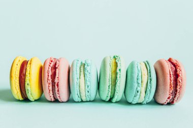Tatlı badem rengi pembe mavi sarı badem kurabiyesi ya da modayı takip eden mavi pastada izole edilmiş badem kurabiyesi. Fransız kurabiyesi. Asgari gıda fırını konsepti. Düz görünüm kopyalama alanı