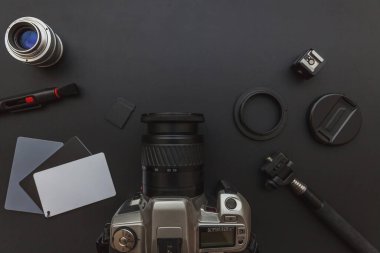 DSR kamera sistemi olan fotoğrafçı işyeri, kamera temizleme seti, siyah masa arka planında lens ve kamera aksesuarı. Hobi seyahat fotoğrafçılık konsepti. Düz görünüm kopyalama alanı