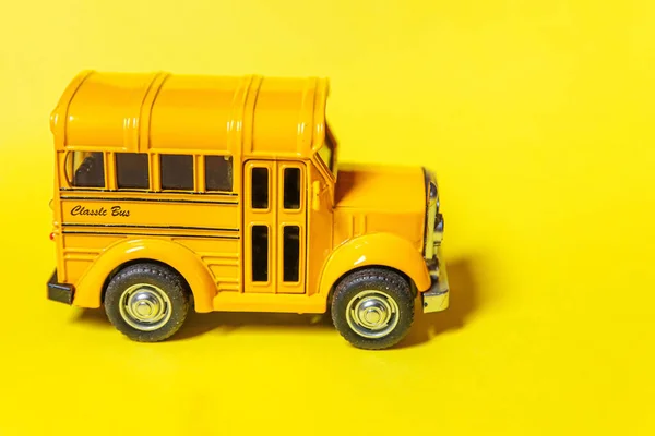 黄色のカラフルな背景に隔離された黄色の古典的なおもちゃの車のスクールバスを単に設計します 子供のための安全な毎日の輸送 学校のコンセプトに戻る 教育のシンボル スペースのコピー — ストック写真