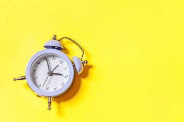 Asgari tasarım, sarı arka planda izole edilmiş ikiz klasik alarm saatini çalıyor. Hayatın dinlenme saatleri. İyi sabahlar. Uyanık kalma kavramı. Düz görünüm kopyalama alanı