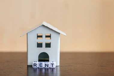Minyatür oyuncak model evi. Üzerinde tahta zemin üzerine yazılmış RENT harfleri var. Eco Village soyut çevre geçmişi. Gayrimenkul ipoteği sigortası tatlı ev ekoloji kira kavramı