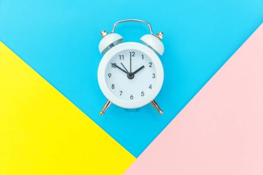 Çalan ikiz çan klasik alarm saati mavi pembe renkli renkli geometrik arkaplanda izole edilmiş. Hayatın dinlenme saatleri. İyi sabahlar. Uyanık kalma kavramı. Düz görünüm kopyalama alanı