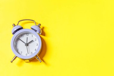 Asgari tasarım, sarı arka planda izole edilmiş ikiz klasik alarm saatini çalıyor. Hayatın dinlenme saatleri. İyi sabahlar. Uyanık kalma kavramı. Düz görünüm kopyalama alanı