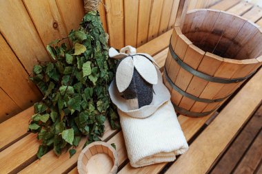İçişleri, geleneksel sauna aksesuarları, süpürge kepçesi kepçeli şapka havlusuyla Finlandiya sauna sauna saunası detaylarını anlatıyor. Geleneksel eski Rus hamamı SPA konsepti. Rahatlayın köy banyosu konsepti.