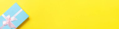 Noel yeni yıl sevgililer günü kutlaması. Romantik bir hediye. Asgari tasarım mavi hediye kutusu sarı renkli arka planda izole edilmiş. Düz görünüm kopyalama alanı, afiş