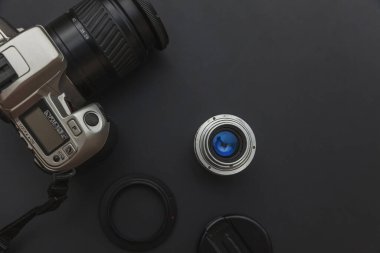 Karanlık masa arka planında DSR kamera sistemi ve lensleri olan fotoğrafçı işyeri. Hobi seyahat fotoğrafçılık konsepti. Düz görünüm kopyalama alanı.
