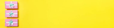Noel yeni yıl sevgililer günü kutlaması. Romantik bir hediye. Asgari tasarım üç pembe hediye kutusu sarı renkli arka planda izole edilmiş. Düz görünüm kopyalama alanı, afiş