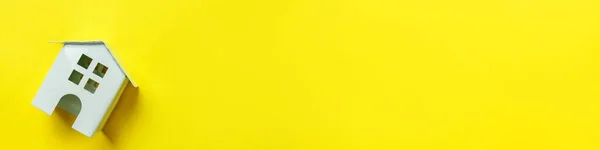 Helt enkelt minimal design med miniatyr vit leksak hus isolerad på gul färgstark bakgrund. Hypoteksförsäkring dröm hem koncept. Platt låg ovanifrån kopiera utrymme banner. — Stockfoto