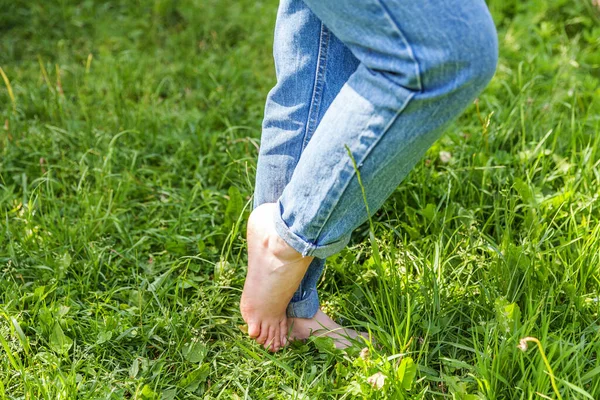 Two beautiful female feet walking on grass in sunny summer morning. Light step barefoot girl legs on soft spring lawn in garden or park. Healthy freedom relax concept