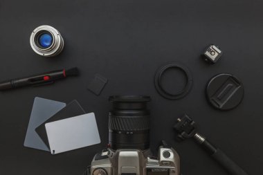 DSR kamera sistemi olan fotoğrafçı işyeri, kamera temizleme seti, siyah masa arka planında lens ve kamera aksesuarı. Hobi seyahat fotoğrafçılık konsepti. Düz görünüm kopyalama alanı