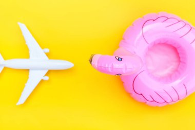 Yaz kumsalı kompozisyonu. Uçak ve sarı zemin üzerinde izole edilmiş şişirilebilir flamingo ile minimum basit düz yatıyordu. Seyahat macerası konsepti. Üst görünüm kopyalama alanı