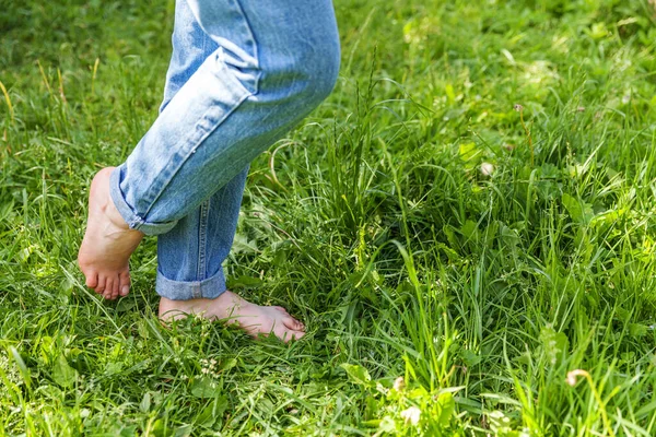 Two beautiful female feet walking on grass in sunny summer morning. Light step barefoot girl legs on soft spring lawn in garden or park. Healthy freedom relax concept