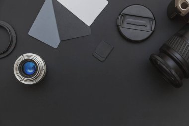 DSR kamera sistemi olan fotoğrafçı işyeri, kamera temizleme seti, siyah masa arka planında lens ve kamera aksesuarı. Hobi seyahat fotoğrafçılık konsepti. Düz görünüm kopyalama alanı