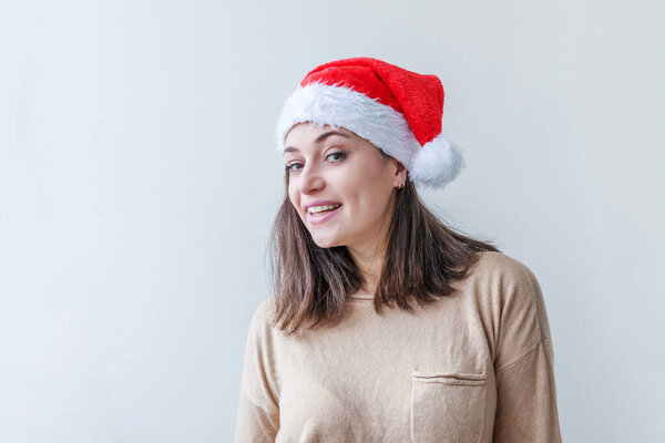 Beautiful girl in red Santa Claus hat isolated on white background looking happy and excited. Young woman portrait, true emotions. Happy Christmas and New Year holidays.