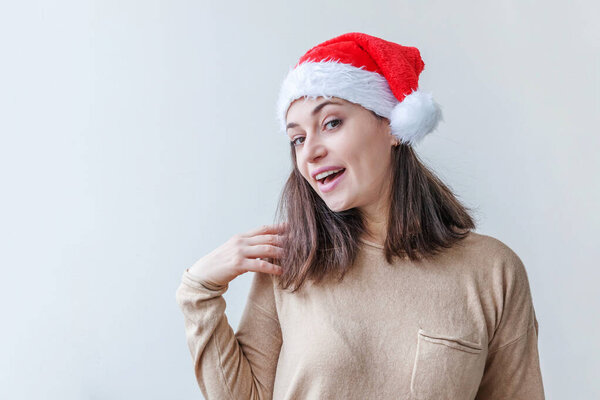 Beautiful girl in red Santa Claus hat isolated on white background looking happy and excited. Young woman portrait, true emotions. Happy Christmas and New Year holidays.