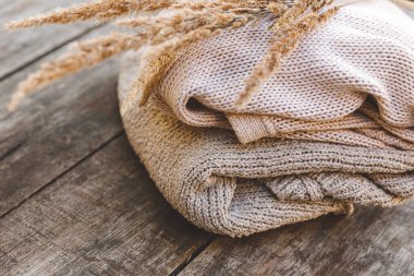 Sonbahar ya da kış geçmişi. Bir yığın yün kazak ve ahşap masada kurutulmuş bitki. Hygge havası, soğuk hava konsepti. El yapımı örgü kazaklar..