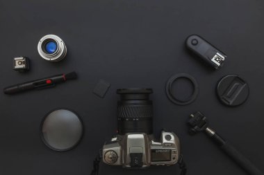 DSR kamera sistemi olan fotoğrafçı işyeri, kamera temizleme seti, siyah masa arka planında lens ve kamera aksesuarı. Hobi seyahat fotoğrafçılık konsepti. Düz görünüm kopyalama alanı