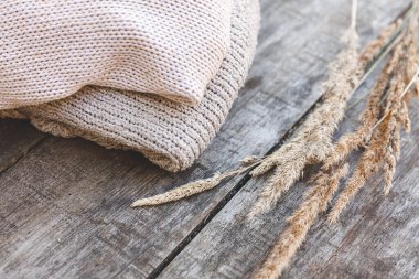 Sonbahar ya da kış geçmişi. Bir yığın yün kazak ve ahşap masada kurutulmuş bitki. Hygge havası, soğuk hava konsepti. El yapımı örgü kazaklar.