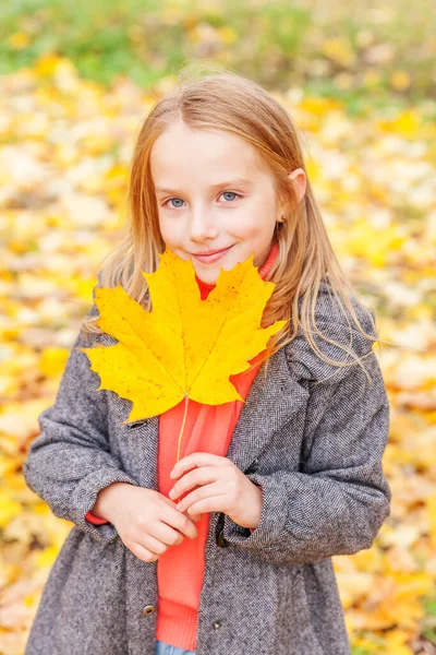自然の中で美しい秋の公園で黄色の葉が落ちると遊ぶ幸せな若い女の子は屋外で歩きます 秋のオレンジのカエデの葉を持つ小さな子供 — ストック写真