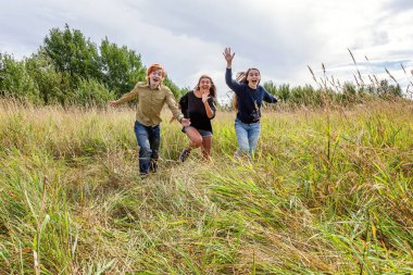 Yaz tatili mutlu insanlar konsepti. Üç arkadaş grubu erkek ve iki kız dışarıda koşup eğleniyorlar. Arkadaşlarla pikniğe gidiyoruz.