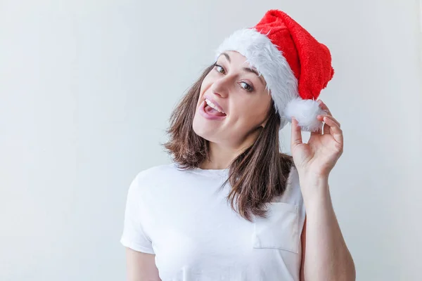 Beautiful girl in red Santa Claus hat isolated on white background looking happy and excited. Young woman portrait, true emotions. Happy Christmas and New Year holidays.