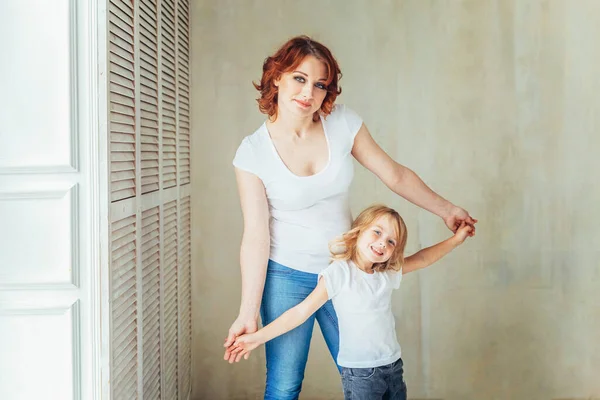 Restez à la maison Restez en sécurité. Jeune mère tenant son enfant. Femme et petite fille se détendant dans une chambre blanche près de windiow à l'intérieur. Bonne famille à la maison. Jeune maman jouant avec sa fille. — Photo