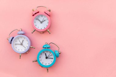 Pembe pastel arka planda izole edilmiş, çalan üç adet klasik alarm saati. Hayatın dinlenme saatleri. İyi sabahlar. Uyanık kalma kavramı. Düz görünüm kopyalama alanı