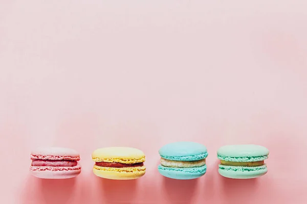 Sweet almond colorful pink blue yellow green macaron or macaroon dessert cake isolated on trendy pink pastel background. French sweet cookie. Minimal food bakery concept. Flat lay top view copy space