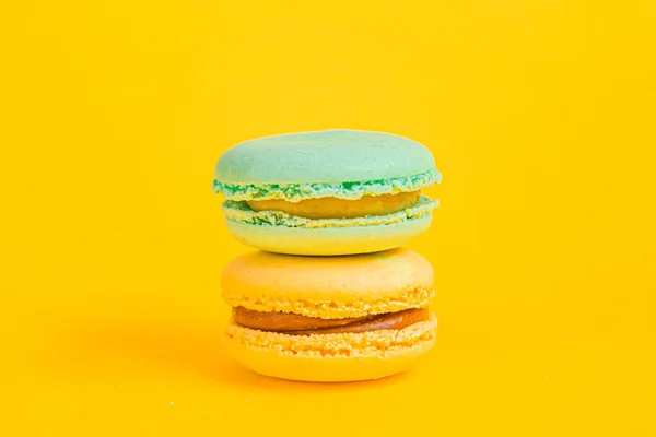 Sweet almond colorful unicorn blue yellow macaron or macaroon dessert cake isolated on trendy yellow modern fashion background. French sweet cookie. Minimal food bakery concept. Copy space