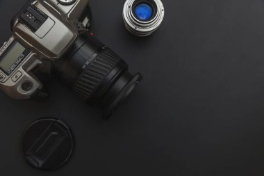Karanlık masa arka planında DSR kamera sistemi ve lensleri olan fotoğrafçı işyeri. Hobi seyahat fotoğrafçılık konsepti. Düz görünüm kopyalama alanı