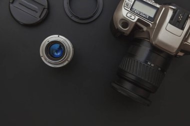 Karanlık masa arka planında DSR kamera sistemi ve lensleri olan fotoğrafçı işyeri. Hobi seyahat fotoğrafçılık konsepti. Düz görünüm kopyalama alanı