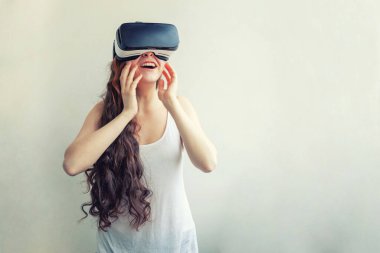 Beyaz arka planda sanal gerçeklik gözlüğü başlığı takan genç kadın gülümse. Sanal gerçeklik gözlüğü takan akıllı telefon. Teknoloji, simülasyon, yüksek teknoloji, video oyunu konsepti