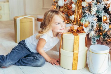 Noel arifesinde Noel ağacının yanında hediye kutusu olan küçük bir kız. Kış dekorasyonuyla aydınlık odada genç bir çocuk. Evde mutlu bir aile. Noel Yeni Yıl Kutlama Konsepti Zamanı.