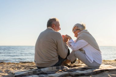 Sahilde oturmuş el ele tutuşan olgun bir çift dışarıda eğleniyor. Yaşlı karı şefkatle el ele tutuşuyor. Büyükannem ve büyükbabam birlikte. Aile âşkı