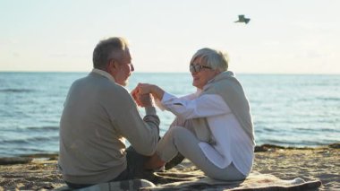 Sahilde oturmuş el ele tutuşan olgun bir çift dışarıda eğleniyor. Yaşlı karı şefkatle el ele tutuşuyor. Büyükannem ve büyükbabam birlikte. Aile âşkı
