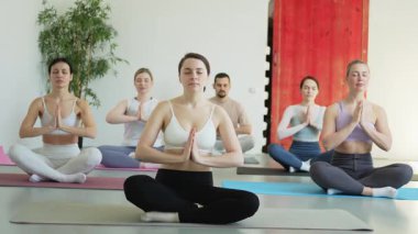 Yoga farkındalığı meditasyonu. Yoga sağlık farkındalığı meditasyonu için stüdyoda egzersiz yapan bir grup sporcu. Nilüfer çiçeğinde oturup yoga yapan erkek kadınlar meditasyon yapıyor.