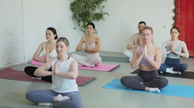 Yoga farkındalığı meditasyonu. Yoga sağlık farkındalığı meditasyonu için stüdyoda egzersiz yapan bir grup sporcu. Nilüfer çiçeğinde oturup yoga yapan erkek kadınlar meditasyon yapıyor.