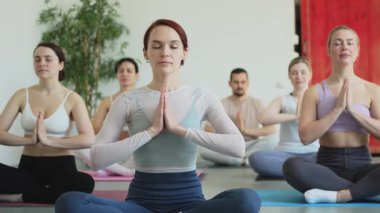 Yoga farkındalığı meditasyonu. Yoga sağlık farkındalığı meditasyonu için stüdyoda egzersiz yapan bir grup sporcu. Nilüfer çiçeğinde oturup yoga yapan erkek kadınlar meditasyon yapıyor.